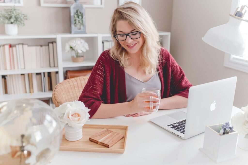 Smiling woman in her 40s working on a laptop at home, representing digital marketing for beginners
